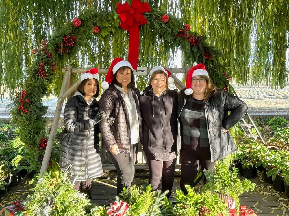 4 women standing below the 8 ft. Christmas wreath at HvH Specialty Growers in Fairfield, California