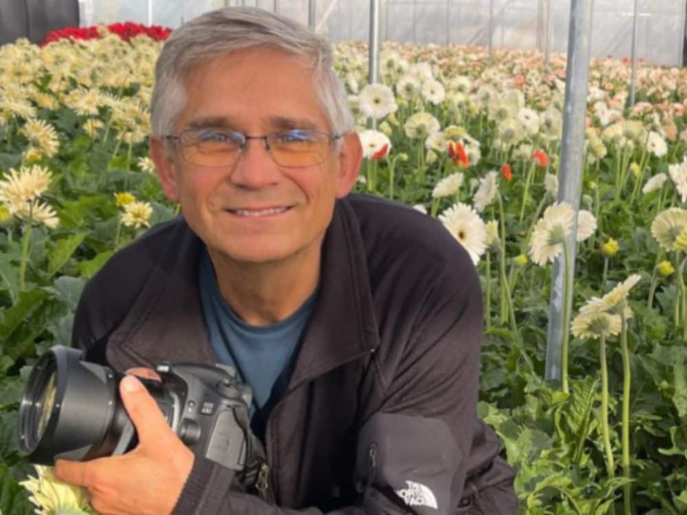 Ron, owner of HvH Specialty Growers in Fairfield, California standing amongst the flowers with his camera