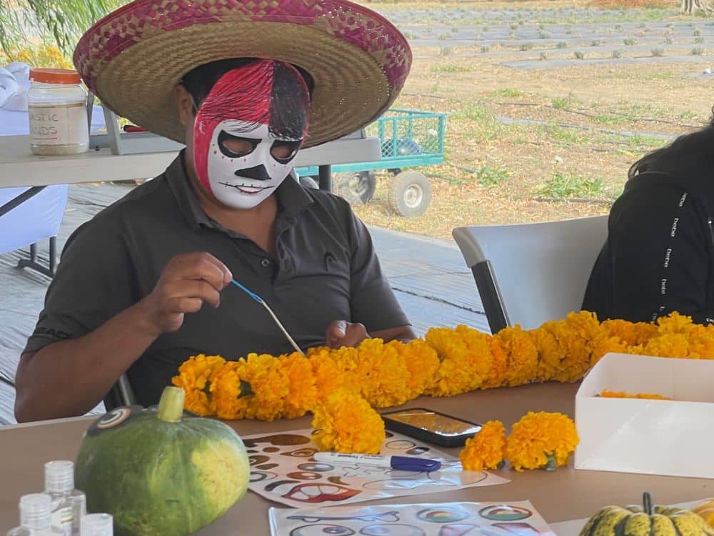 Person making a yellow marigold garland made with fresh cut marigolds at HvH Specialty Growers in Fairfield, California