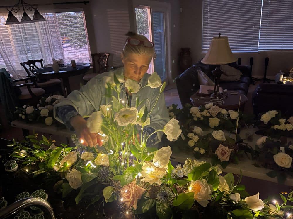 Lisa, owner of Tabletop Alchemist putting the finishing touches on a custom lit flower arrangement
